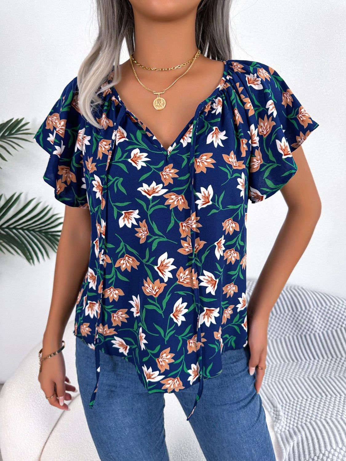 Blusa floral con cuello anudado y mangas acampanadas